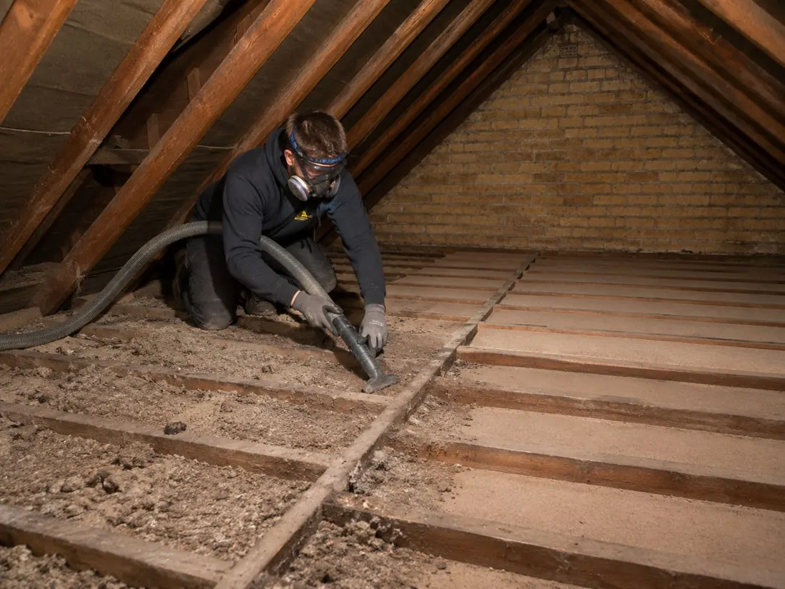 Old loft insulation being bagged up for removal from a loft